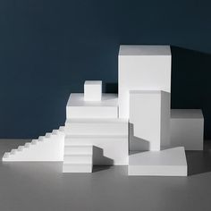 several white blocks stacked on top of each other in front of a dark blue wall