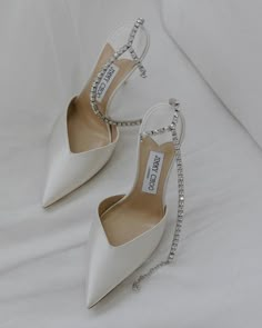 a pair of white high heeled shoes sitting on top of a bed