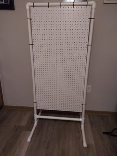 a white rack with pegs on it in the corner next to a wall mounted television