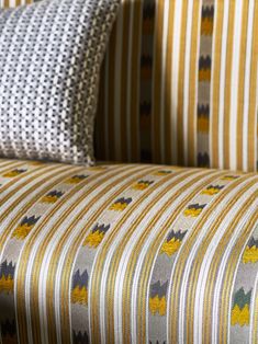 an upholstered couch with yellow and grey striped fabric on it's back