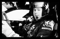 a man sitting in the driver's seat of a car wearing a helmet and holding a steering wheel