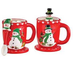 two red mugs with snowmen on them, one is holding a spoon and the other has a green hat