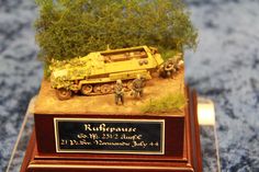 a miniature army vehicle is on display in a glass case with a plaque underneath it