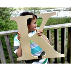 a young boy holding up the letter k to make it look like he is standing on a deck