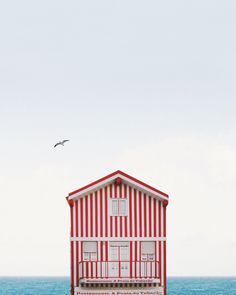 a red and white house sitting on top of a sandy beach