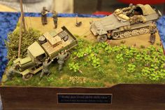 some toy soldiers are playing with an army vehicle and truck in the grass on top of a wooden box