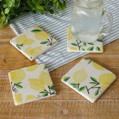 four lemon coasters sitting on top of a wooden table next to a mason jar