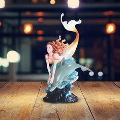 a mermaid figurine sitting on top of a wooden table