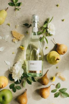 a bottle of wine surrounded by pears and flowers