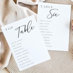 two place cards with names on them sitting on top of a cloth covered tablecloth