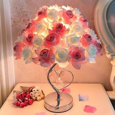 a lamp that is on top of a table with flowers in the shape of a heart