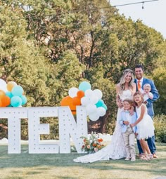 a group of people standing next to each other in front of a sign with balloons