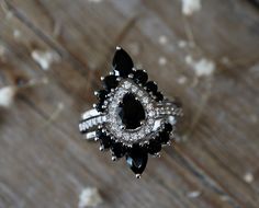 a black and white diamond ring sitting on top of a wooden table next to dried flowers