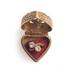 an open heart shaped box with two rings inside