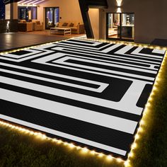 a large black and white rug with lights on it in front of a house at night