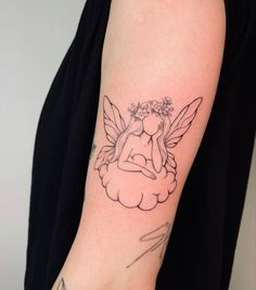 a woman's arm with a tattoo on it that has an angel sitting on top of a cloud