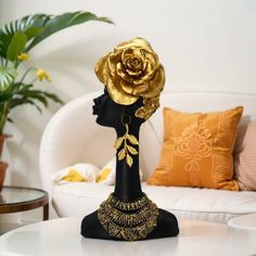 a black mannequin head with a gold rose on it