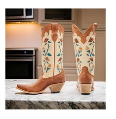 Idyllwind Women's Rosie Western Boots (Medium Sizes). This stylish boot features a tan leather upper with a snip toe design, making it perfect for dressing up or adding a touch of cowboy style to your everyday look. The pull tabs make it easy to slip on and off, while the leather upper provides a comfortable and breathable fit. The floral embroidery and inlay design on the shaft add a touch of whimsy and charm, making this boot a standout piece. The western heel gives the boot a classic cowboy s Cream Boots With Reinforced Heel And Snip Toe, Cream Snip Toe Boots With Reinforced Heel, Western Snip Toe Boots With Heel Tab, Cream Snip Toe Boots With Leather Sole, Beige Snip Toe Boots With Reinforced Heel, Western Cream Boots With Reinforced Heel, Western Cream Snip Toe Heeled Boots, Cream Western Boots With Reinforced Heel, Western Cream Heeled Boots With Snip Toe