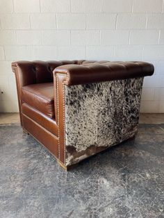 a brown leather chair with cow hide upholstered on the armrests and back