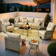 an outdoor living area with wicker furniture and candles on the fire pit at night