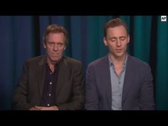 two men sitting next to each other in front of blue curtained walls and green curtains