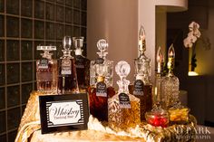 a table topped with lots of bottles of liquor next to a sign that says what does it