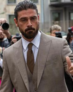 a man in a suit and tie giving the thumbs up sign with cameras around him