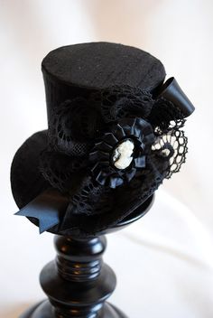 This victorian goth mini top hat is a simple yet elegant piece.It is covered with black silk shantung and adorned with black satin ribbon in a vertical half bow, vintage black cotton lace in a rosette, pleated satin ribbon, which forms an oval frame for a beautiful black and white victorian profile cameo. Choose between with or without black veil. Also available in a white and black combination: https://www.etsy.com/bizarrenoir/listing/166826619/gothic-mini-top-hat-in-purple-velvet?ref=shop_home Gothic Black Brimmed Costume Hat, Black Gothic Mini Hats For Costume Party, Black Gothic Party Hat, Gothic Black Top Hat For Costume Party, Gothic Top Hat With High Crown For Parties, Black Gothic Mini Hat Adjustable, Black Gothic Top Hat For Costume Party, Gothic Top Hat With Short Brim For Halloween, Black Gothic Mini Hat With Adjustable Fit