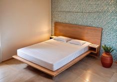 a bed sitting in the middle of a bedroom next to a wall with a plant on it