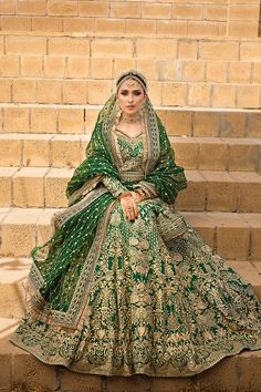 a woman in a green and gold wedding dress sitting on some steps