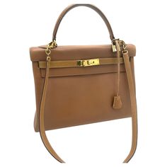 Hermés 2 way Kelly bag, Retourne, 32 cm, Curchevel leather in gold, Collection L in circle = 1982 with long autentic Strap, Lock and Key and Hermes dustbag included. MADE IN FRANCE Measurement: Height 22 cm Lenght 32 cm Deep 10 cm Strap 65 cm The Kelly bag is in very good condition for its time. The handle is in perfect original condition, the 4 corners at the bottom of the bag are in good original condition. The front of the Kelly unfortunately had many fingernail scratches. For this reason, th Gold Satchel Shoulder Bag With Brass Hardware, Classic Beige Bags With Brass Hardware, Gold Satchel With Brass Hardware For Office, Office Gold Satchel With Brass Hardware, Classic Gold Satchel With Brass Hardware, Business Bags With Brass Hardware And Top Handle, Gold Shoulder Bag With Brass Hardware For Travel, Beige Satchel Bag With Brass Hardware, Designer Beige Bags With Brass Hardware