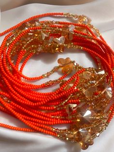 Single Strand Waist Bead Ahigbé is a beautiful and unique accessory that combines style with cultural heritage. This waist bead features a stunning combination of orange and silver beads, creating a bold and eye-catching design. The waist bead is strung on durable woven cord that can be easily adjusted to fit a variety of waist sizes. The beads are meticulously arranged to ensure a smooth and comfortable fit against the skin, making it perfect for all-day wear. Whether you're dressing up or dres Bohemian Orange Beaded Bracelets With Large Beads, Traditional Orange Necklace For The Beach, Adjustable Coral Beaded Necklace With Large Beads, Adjustable Large Bead Coral Necklace, Traditional Orange Beaded Bracelets For Festivals, Handmade Orange Beaded Bracelets For Party, Handmade Orange Beaded Bracelets Spiritual Style, Orange Polished Beaded Necklaces, Orange Polished Round Beaded Necklaces