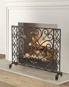 a fireplace with a fire in it on top of a hard wood floor next to a white wall