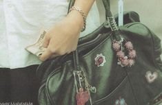 a woman is holding a purse with many charms on it and her hands are in the pocket