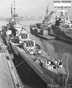 an old photo of a battleship docked in the water with other ships behind it and another ship nearby