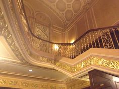 an ornate stair case in a building with gold paint on the walls and railings