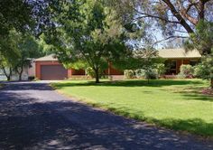 a driveway leading to a house with trees and grass