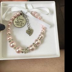 a pink bracelet with a heart charm is in a white box and has a tag on it