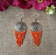 two orange and silver earrings on a table