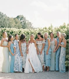 a group of women standing next to each other wearing dresses and holding hands in their pockets