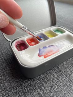 a person is painting with watercolors in a small box