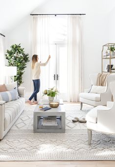 a living room filled with furniture and a white rug on top of a hard wood floor