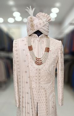 the back of a white dress with beads on it and a turban hat