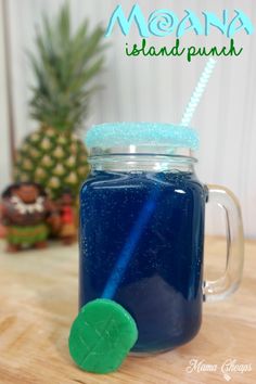 a mason jar filled with blue liquid next to a pineapple