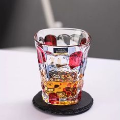 a glass filled with liquid sitting on top of a white table next to a black coaster