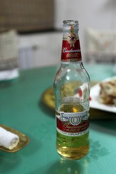 a bottle of beer sitting on top of a green table next to plates of food