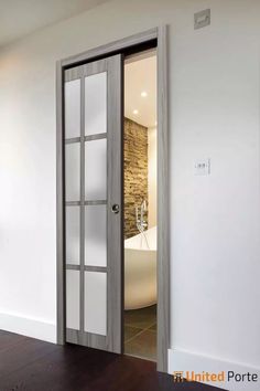 an open door leading to a bathroom with a tub in the corner and wood flooring