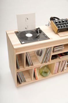 a record player is sitting on top of a wooden shelf with records and vinyls