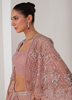 Elevate your style with the stunning Pastel Pink Draped Skirt with Embellished Cape, that effortlessly blends tradition with contemporary elegance. The pink cape features a sophisticated kimono sleeve , adorned with intricate florence embroidery using sequins, crystal tassels, cutdana, and bead highlights, adding a touch of opulence. Paired perfectly with a sequin jaal embellished blouse, it offers a dazzling appeal, making you the center of attention. Completed with a draped skirt, designed for a flattering silhouette, exudes grace and charm, ensuring comfort and sophistication in every movement. Ideal for, this ensemble is a timeless addition to your wardrobe, exuding both modernity and tradition in every detail. Composition : Cape - Organza ,Skirt - Platinoir Crepe Care: Dry Clean Only Pink Wedding Set With Cape Sleeves, Pink Wedding Sets With Cape Sleeves, Pink Cape Sleeves Set With Dupatta, Pink Sets With Dupatta And Cape Sleeves, Pink Dupatta Set With Cape Sleeves, Cape Style Lehenga For Wedding, Pink Cape Sleeves Dress With Sheer Dupatta, Pink Designer Dress With Cape Sleeves, Designer Pink Dress With Cape Sleeves