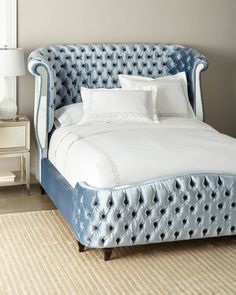 a bed with blue velvet headboard and foot board in a bedroom area next to a window